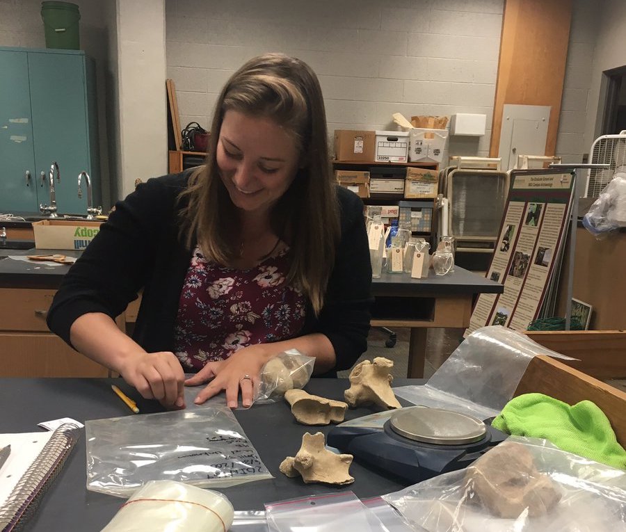 Image of smiling student counting and weighing archaeological animal remains
