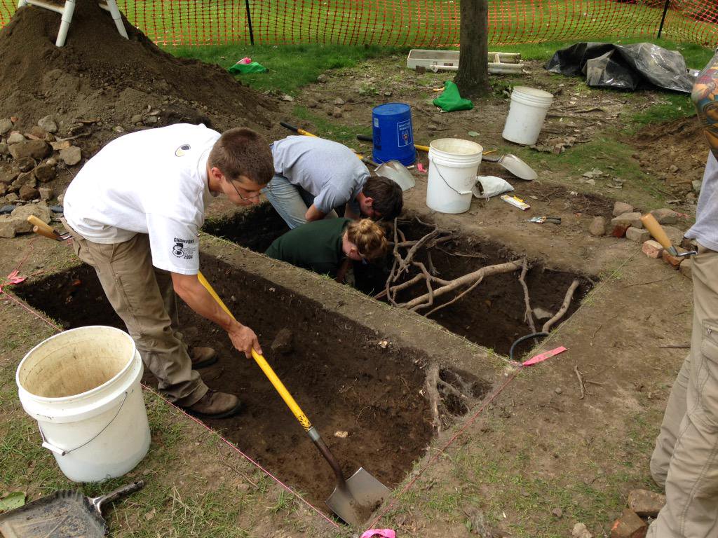 Three students using shovels and trowels to excavate two units